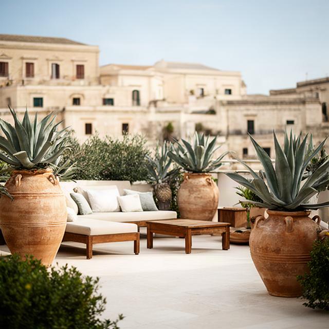 Terrazza privata a Ragusa con grandi vasi, agavi e sedute in legno